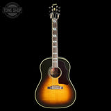 A Gibson acoustic guitar with a natural sunburst finish, shown vertically against a solid black background. The Gibson logo is visible on the headstock, and a Tone Shop watermark is in the top-left corner.