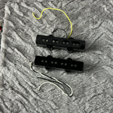 Two black guitar humbucker pickups with attached wires, placed on a textured gray fabric background.