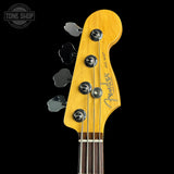 Close-up of a Fender Jazz Bass headstock in natural maple wood with four silver tuning pegs and strings, shown against a black background with a Tone Shop watermark in the top left.