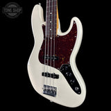 A white electric bass guitar with a dark reddish-brown glitter pickguard, black control plate, and four strings, shown against a solid black background with a Tone Shop logo in the top-left corner.