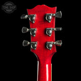 Close-up of a red electric guitar headstock with six silver tuning pegs against a black background. A Tone Shop watermark is visible in the top-left corner.
