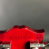 Close-up of the back of a red guitar headstock with visible Grover tuning pegs and a serial number stamped on the wood.