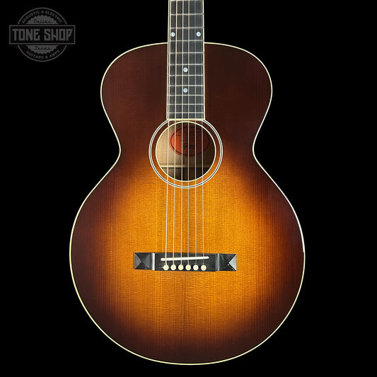 Acoustic guitar with a sunburst finish on a black background, featuring the Tone Shop logo.