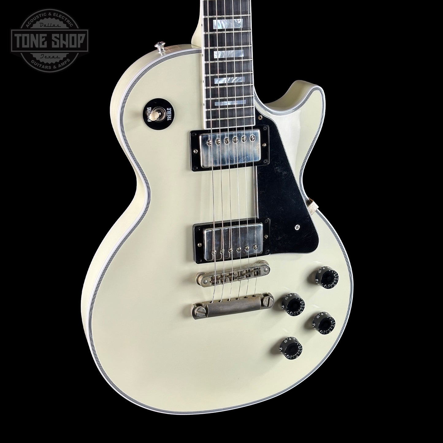 White electric guitar with black details on a black background, featuring 'Tone Shop' branding.