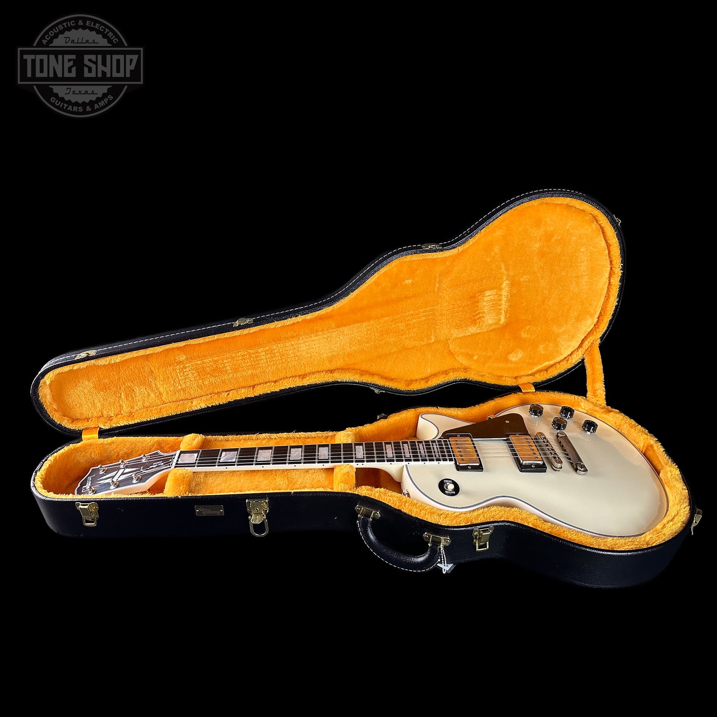 Electric guitar in an open case with 'Tone Shop' logo in the corner.