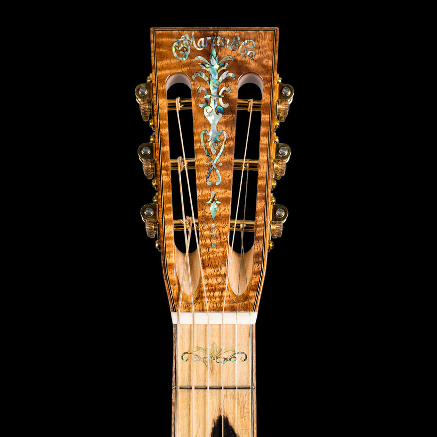 Martin Custom Headstock with inlays and figured wood against a black background.