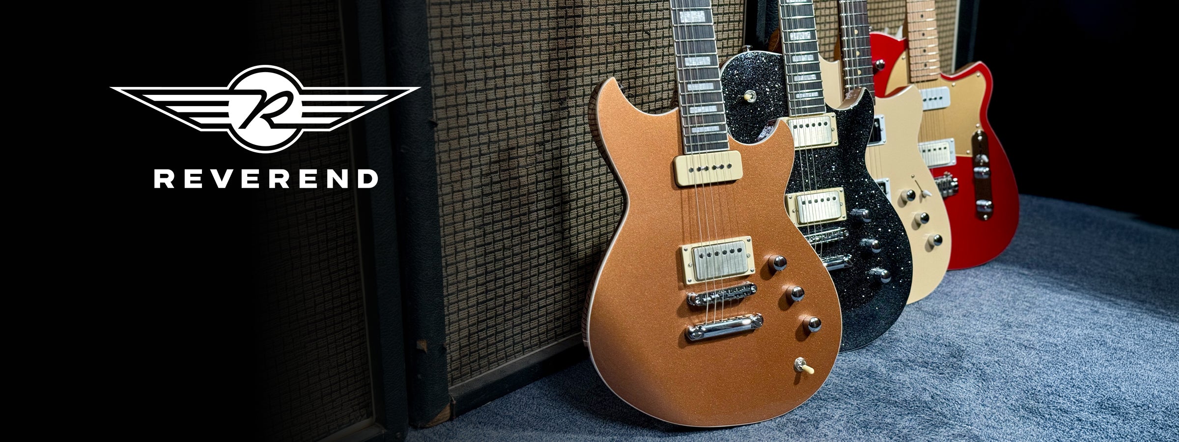 A group of reverend guitars against a basketweave amp cabinet.
