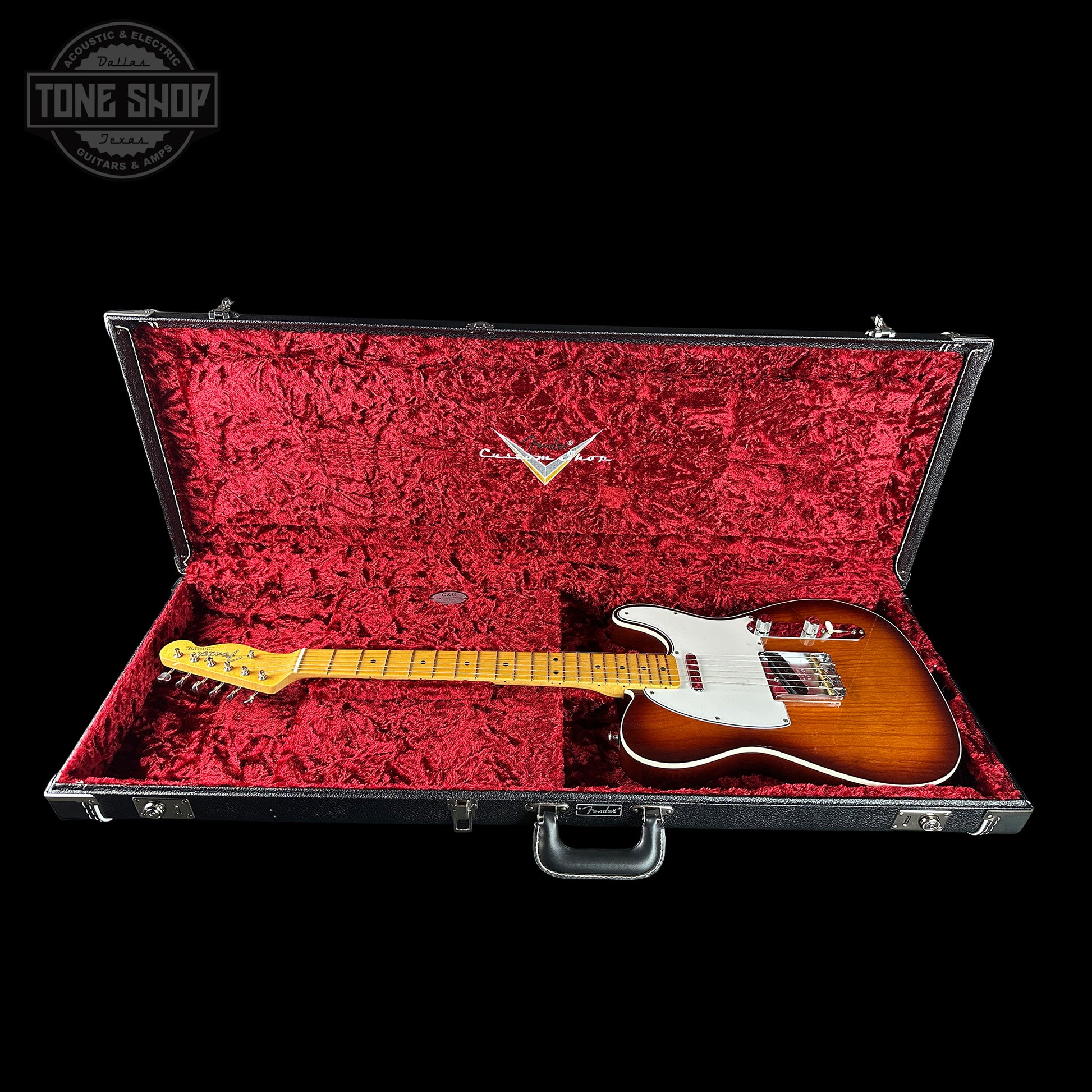 Guitar in a red-lined case with a visible brand logo on a black background