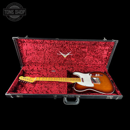 Guitar in a red-lined case with a visible brand logo on a black background