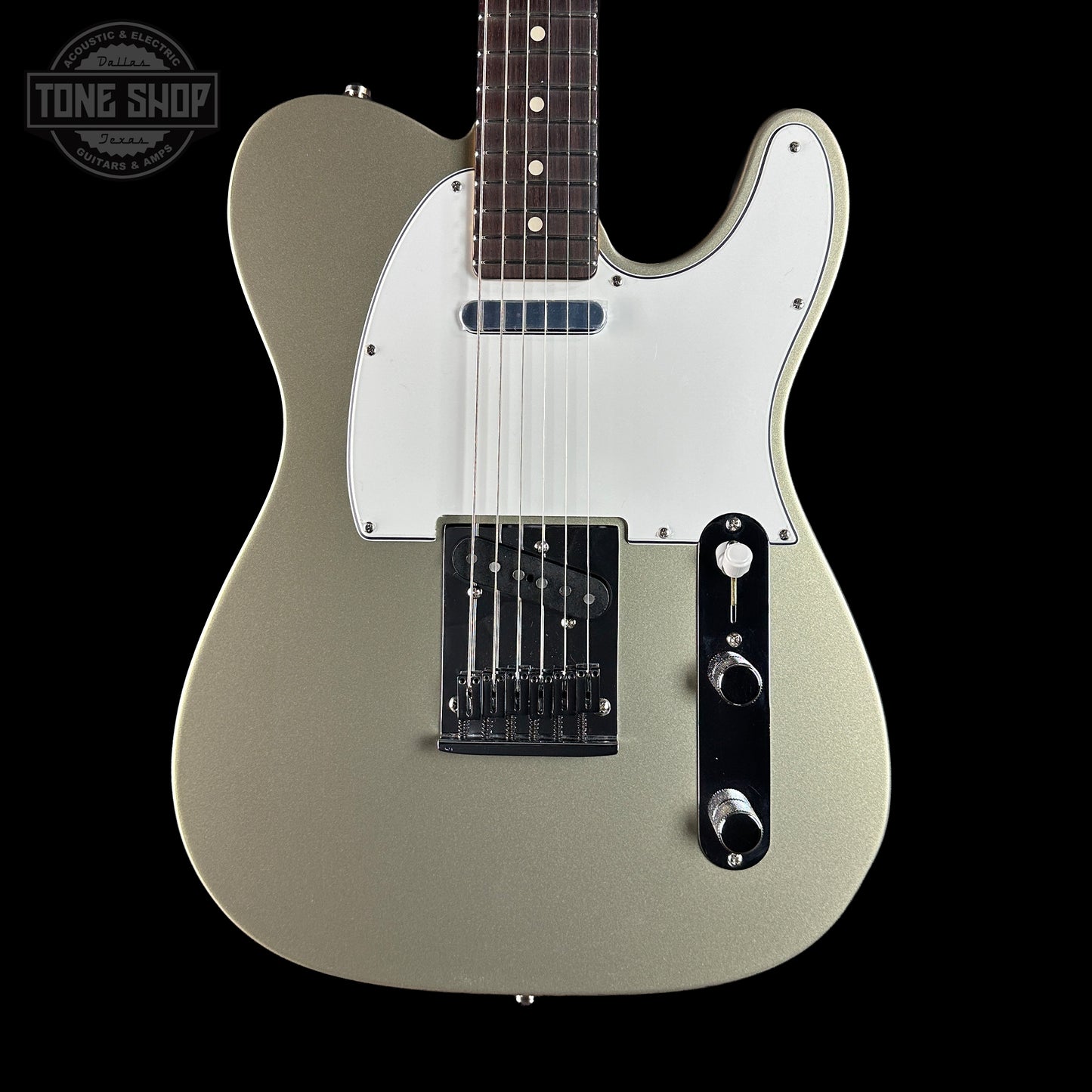 Electric guitar with a silver finish on a black background, featuring the Tone Shop logo.