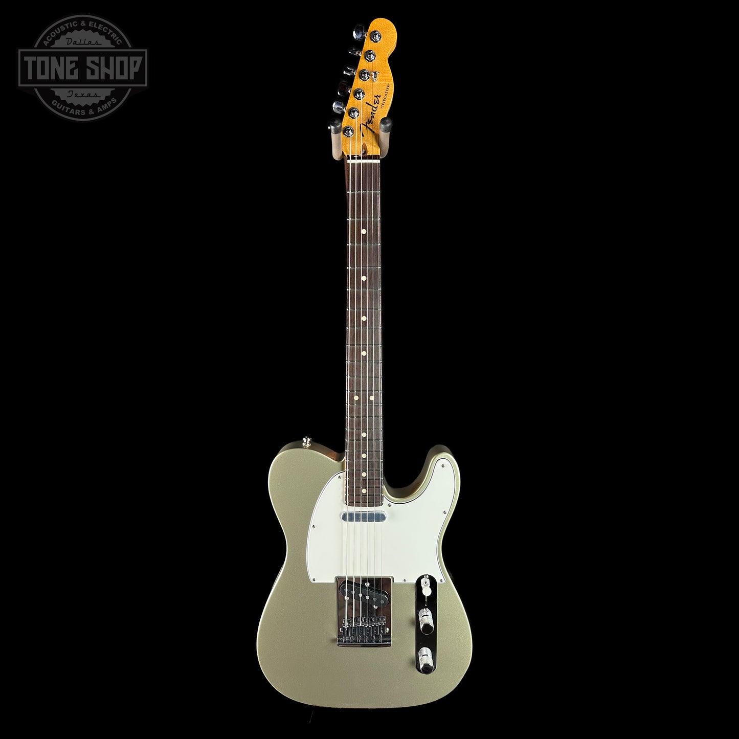 Electric guitar with a white pickguard on a black background, featuring the Tone Shop logo.