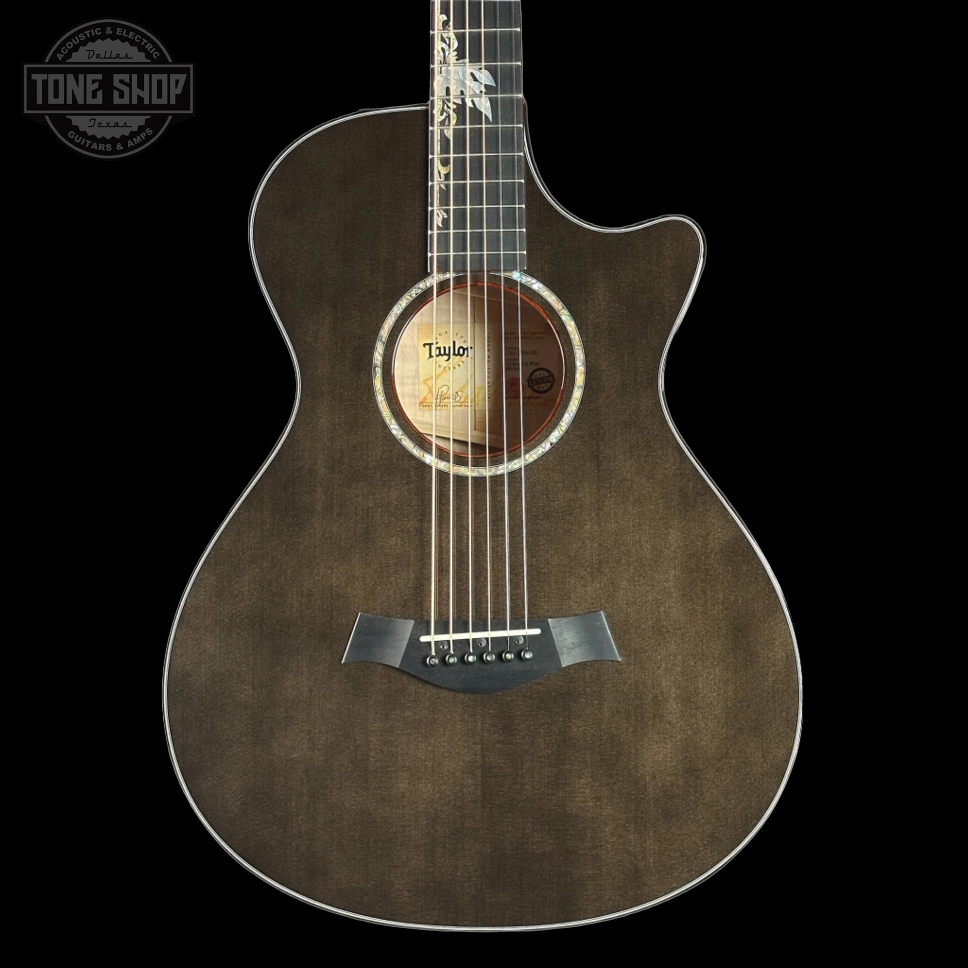 Taylor 2025 Namm Custom Grand Concert 12-Fret Guitar with transparent black color and a case, featuring a sitka spruce top and big leaf maple back and sides.
