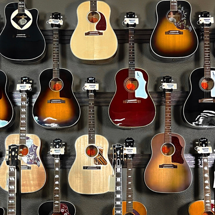 Various acoustic guitars hanging in display showroom at Tone Shop Guitars.