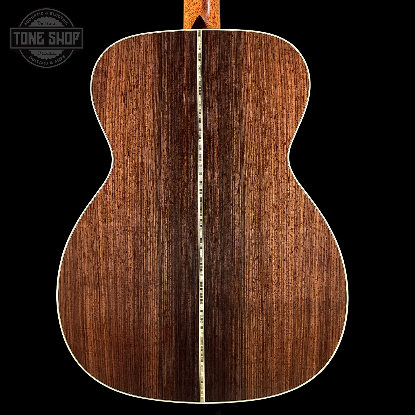 Back view of a wooden acoustic guitar with a visible brand logo in the corner.