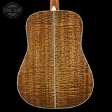 Back view of a wooden acoustic guitar with a visible brand logo in the corner.
