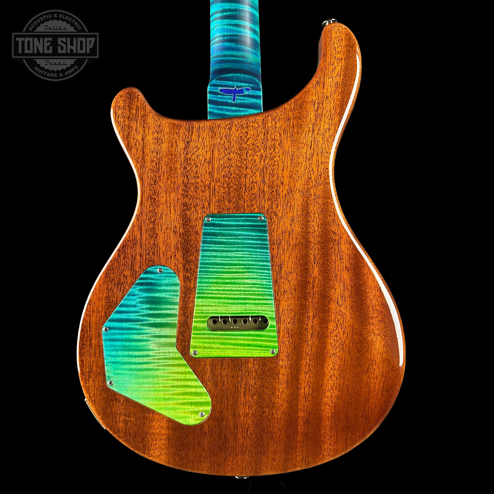 Wooden electric guitar with colorful pickguard on a black background, featuring 'Tone Shop' logo.