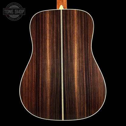 Back view of a wooden acoustic guitar with a visible brand logo in the corner.