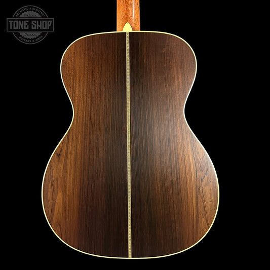 Back view of a wooden acoustic guitar with 'Tone Shop' logo.
