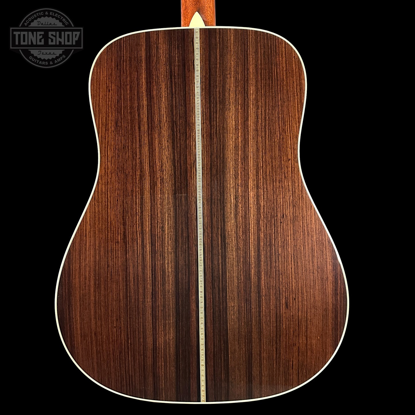 Back of a wooden acoustic guitar with a visible brand logo in the corner.