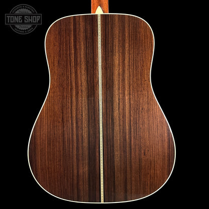 Back of a wooden acoustic guitar with a visible brand logo in the corner.