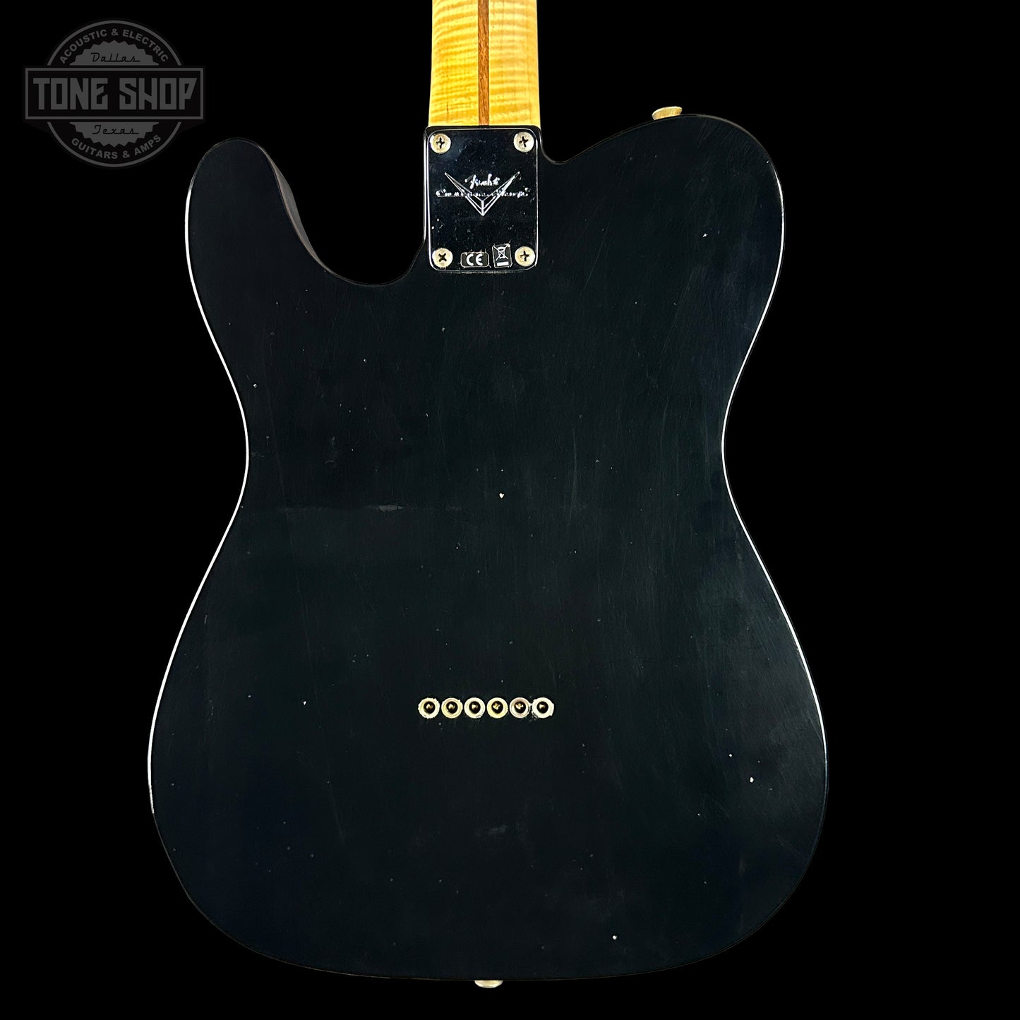 Black electric guitar body with a visible brand logo on a black background