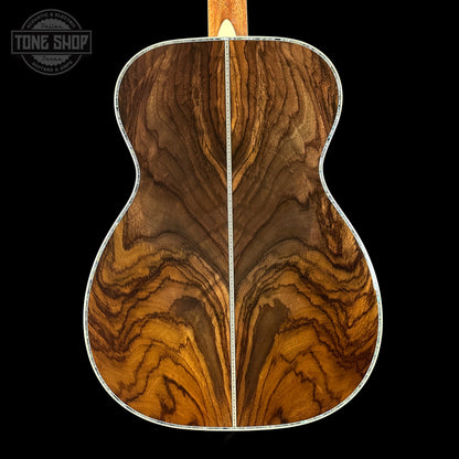 Close-up of a wooden acoustic guitar back with 'Tone Shop' logo.