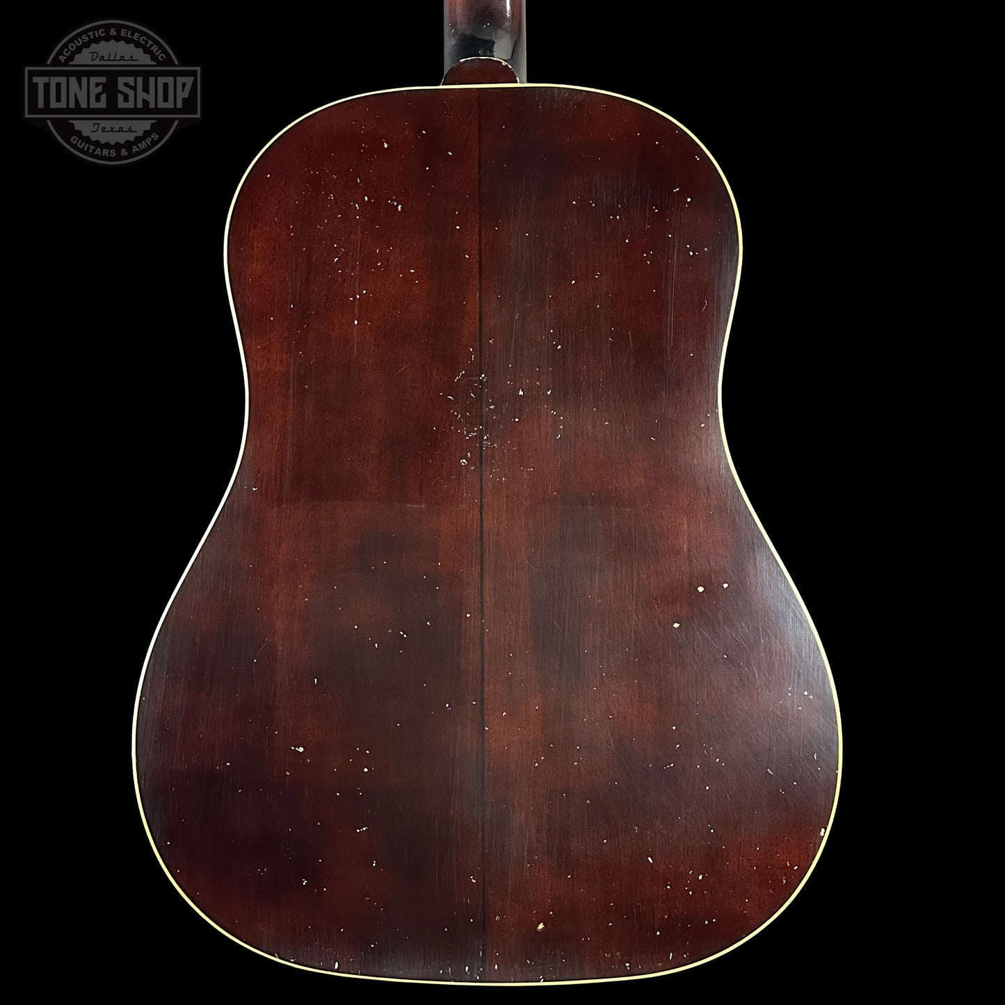 Back view of a wooden acoustic guitar with 'Tone Shop' logo.