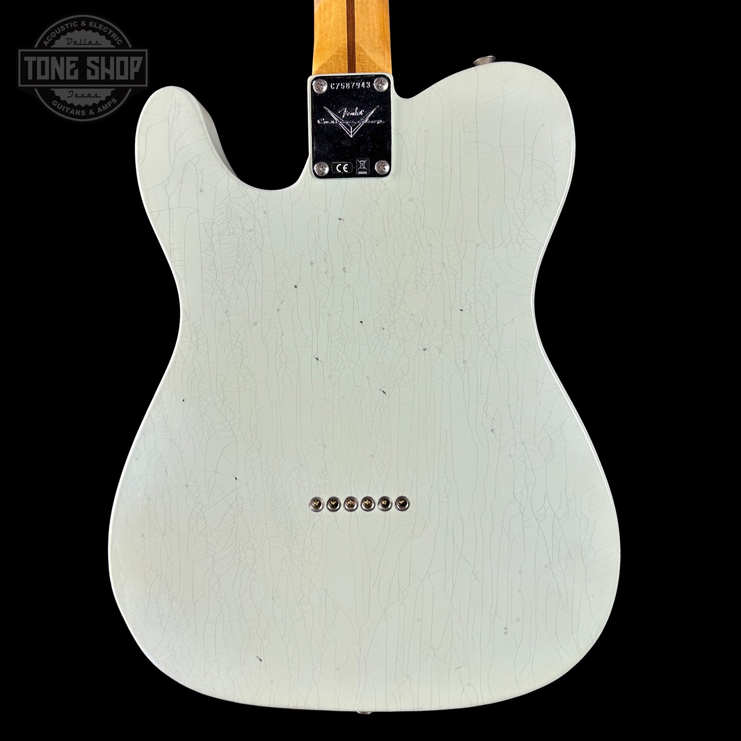 Back of a white electric guitar with a visible Fender logo on a black background
