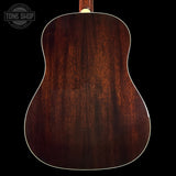 Back view of a wooden acoustic guitar with a dark brown finish on a black background.