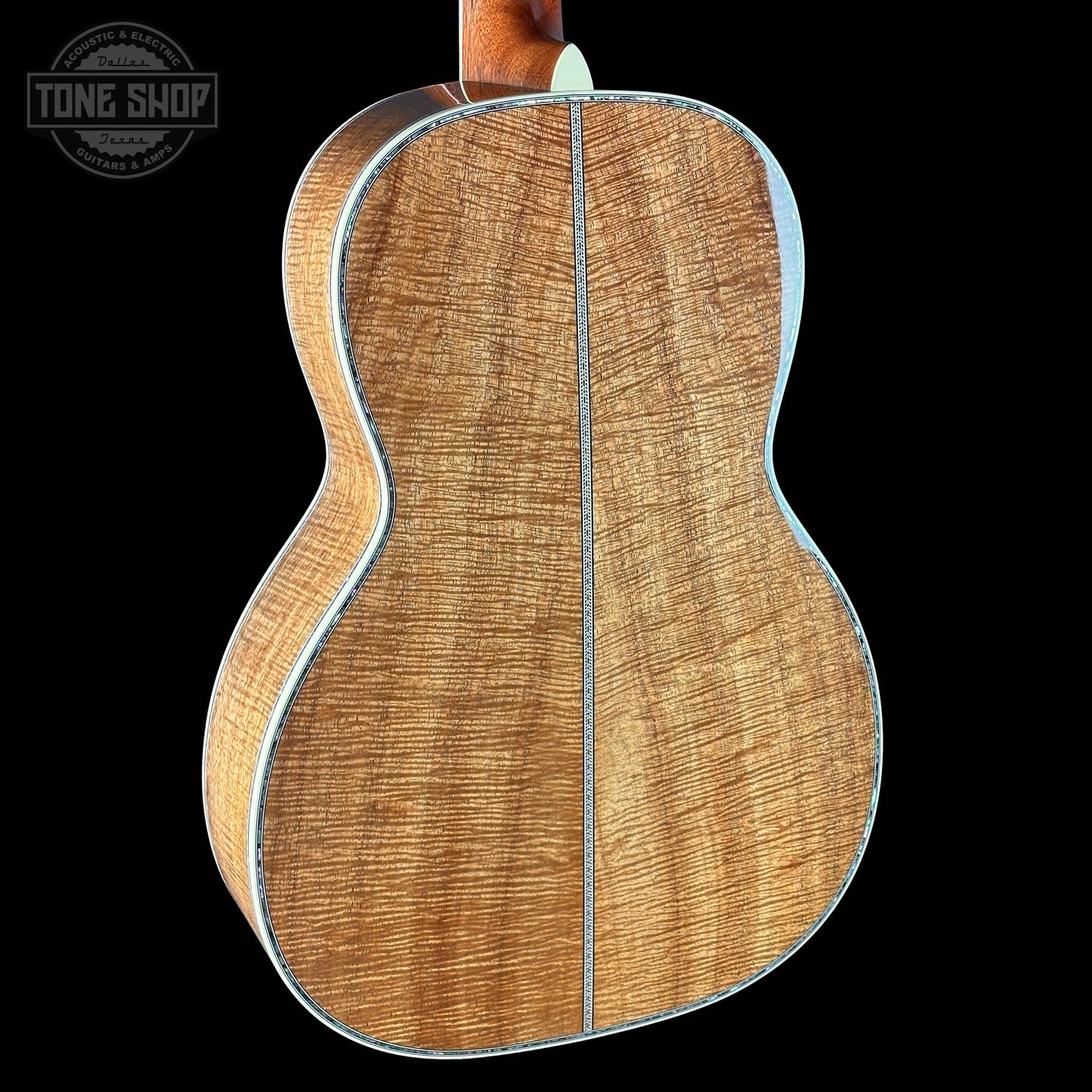 Back view of a wooden acoustic guitar with 'Tone Shop' logo in the corner.