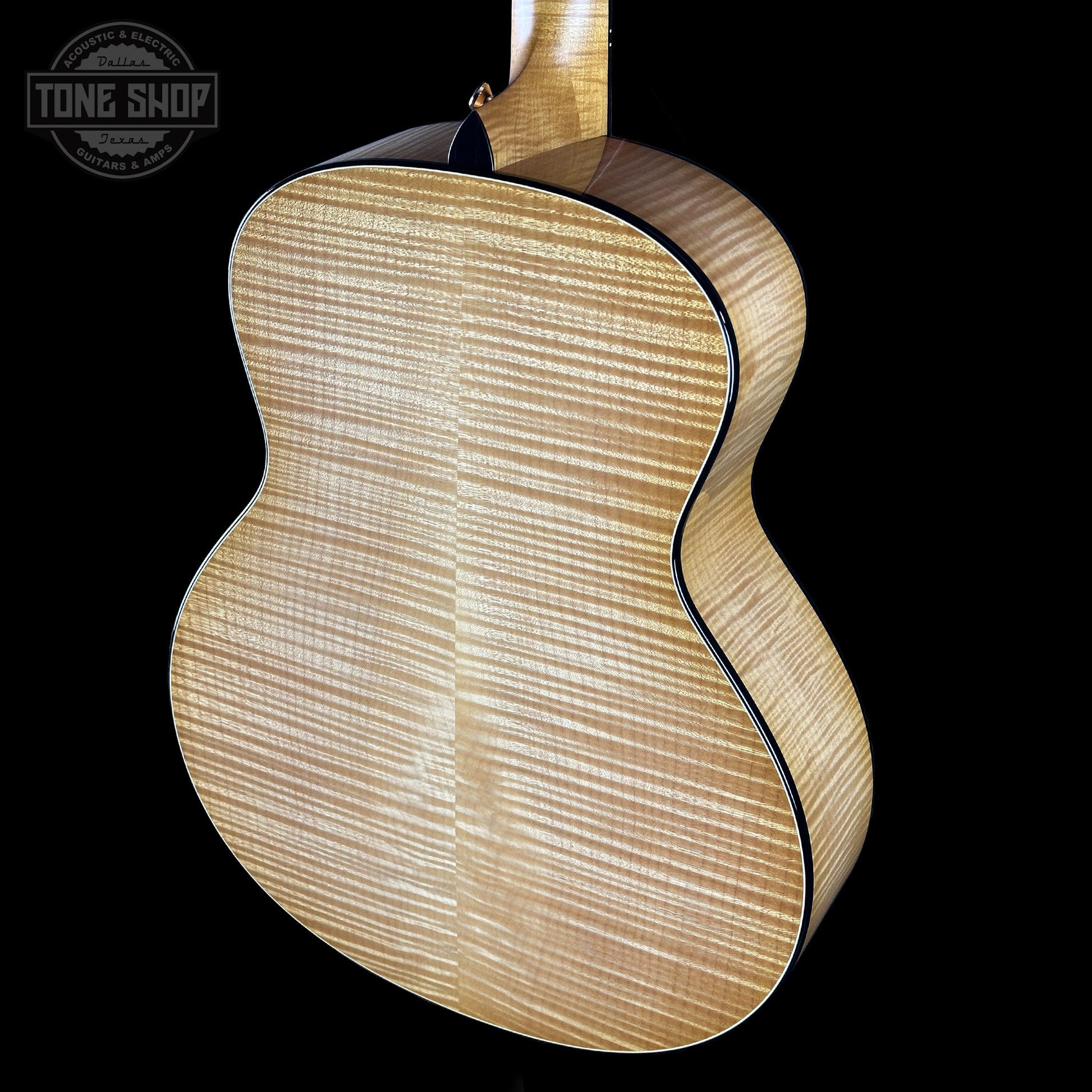 Close-up of a wooden acoustic guitar on a black background with 'Tone Shop' logo.