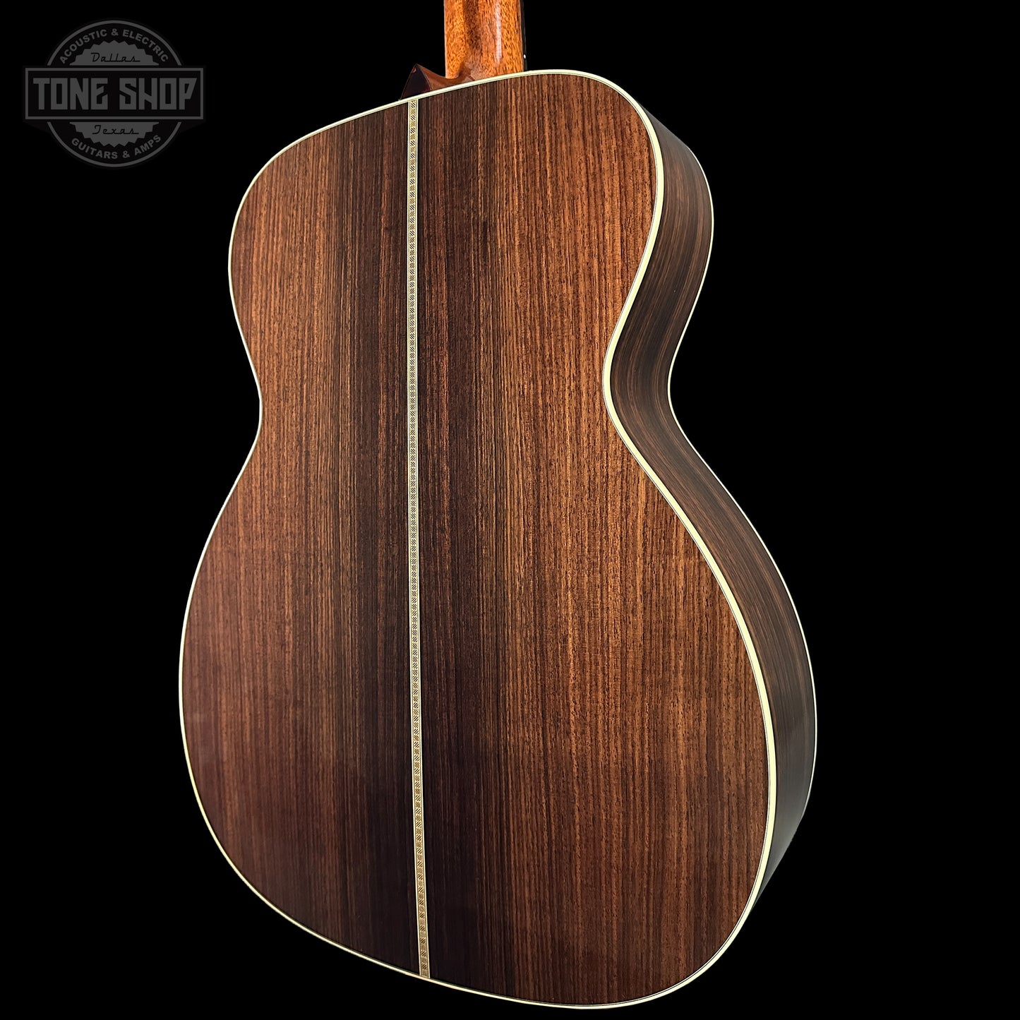 Close-up of a wooden acoustic guitar on a black background with 'Tone Shop' logo.