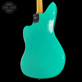 Turquoise electric guitar with a visible brand logo on a black background