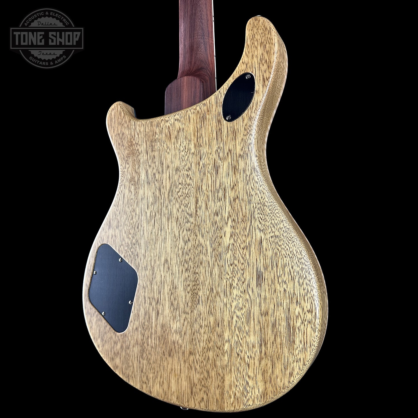 Wooden guitar body with a dark finish on a black background, featuring the Tone Shop logo.