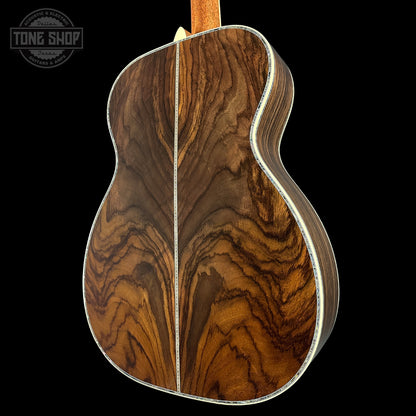 Close-up of a guitar's wooden back with a wavy pattern on a black background, featuring 'Tone Shop' logo.