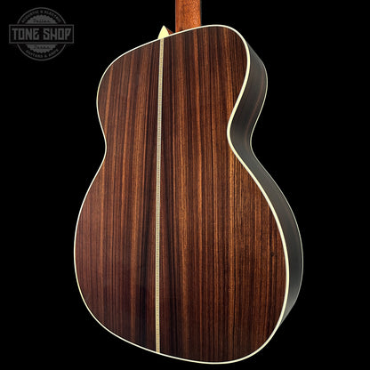 Back view of a wooden acoustic guitar with a visible brand logo in the corner.