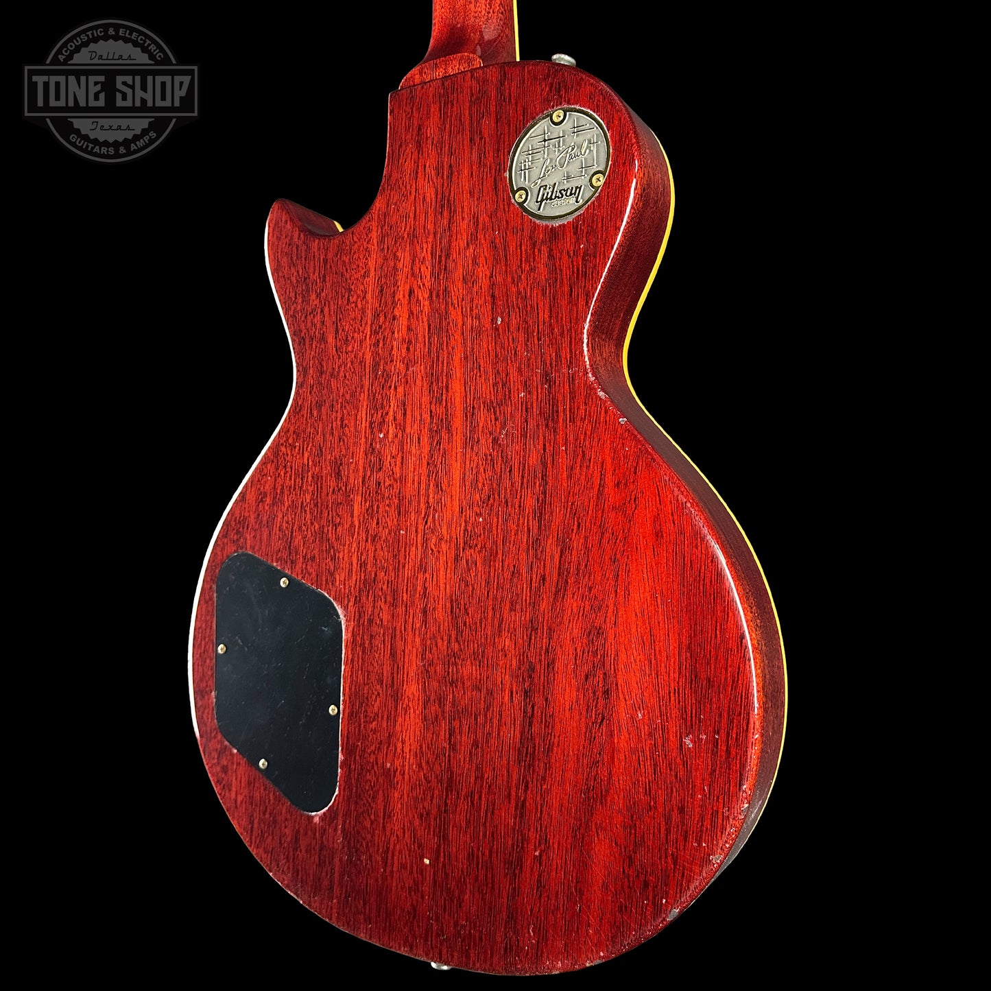 Close-up of a red electric guitar body with a visible brand logo on a black background.