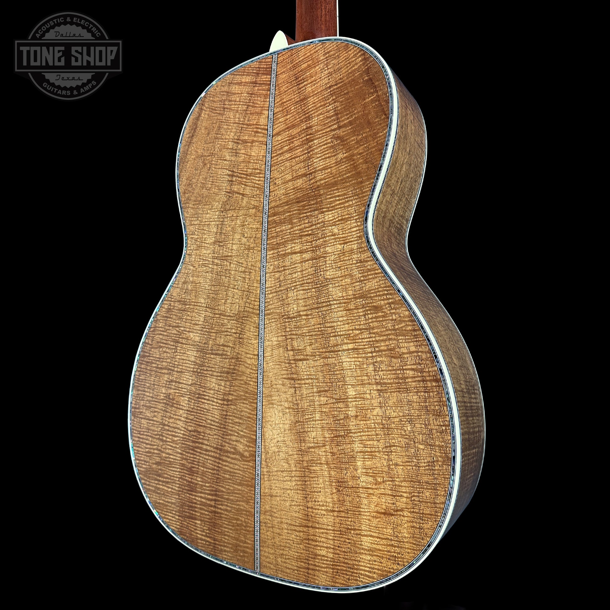 Back view of a wooden acoustic guitar with 'Tone Shop' logo.