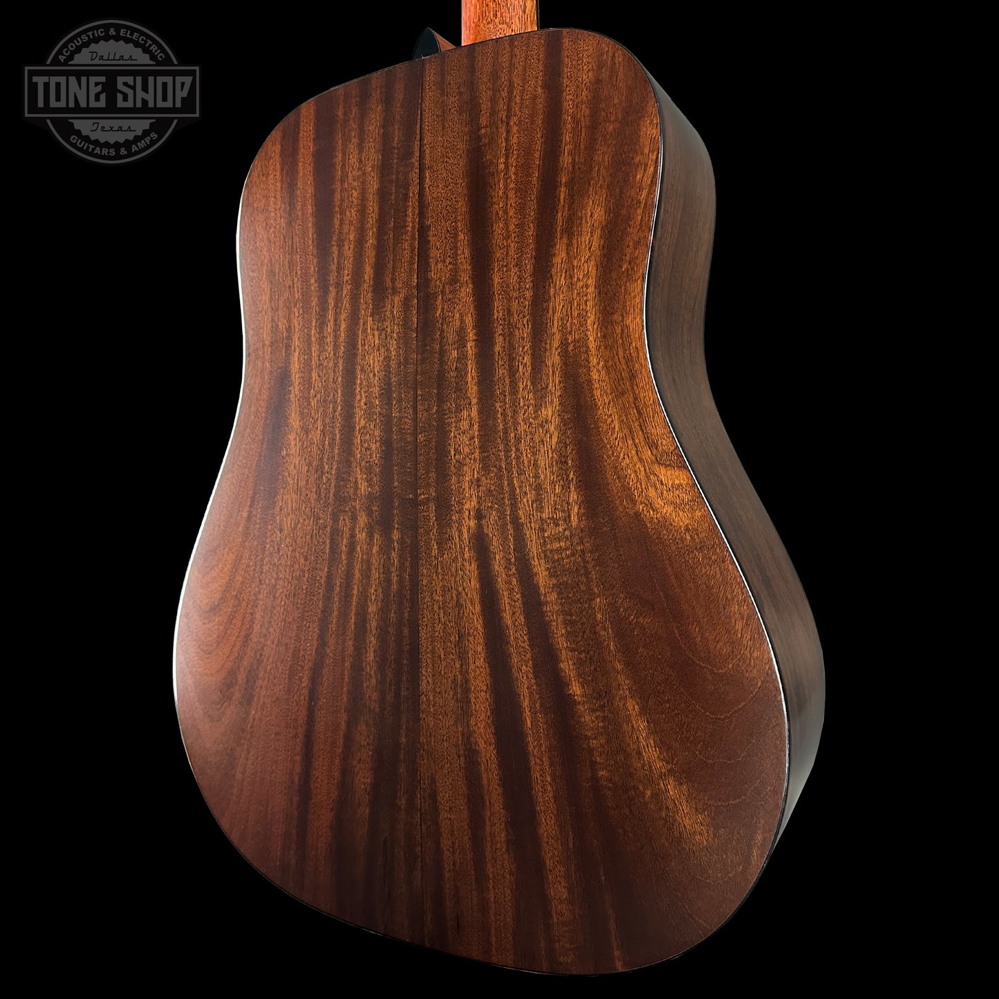 Close-up of a wooden guitar back with 'Tone Shop' logo in the corner.