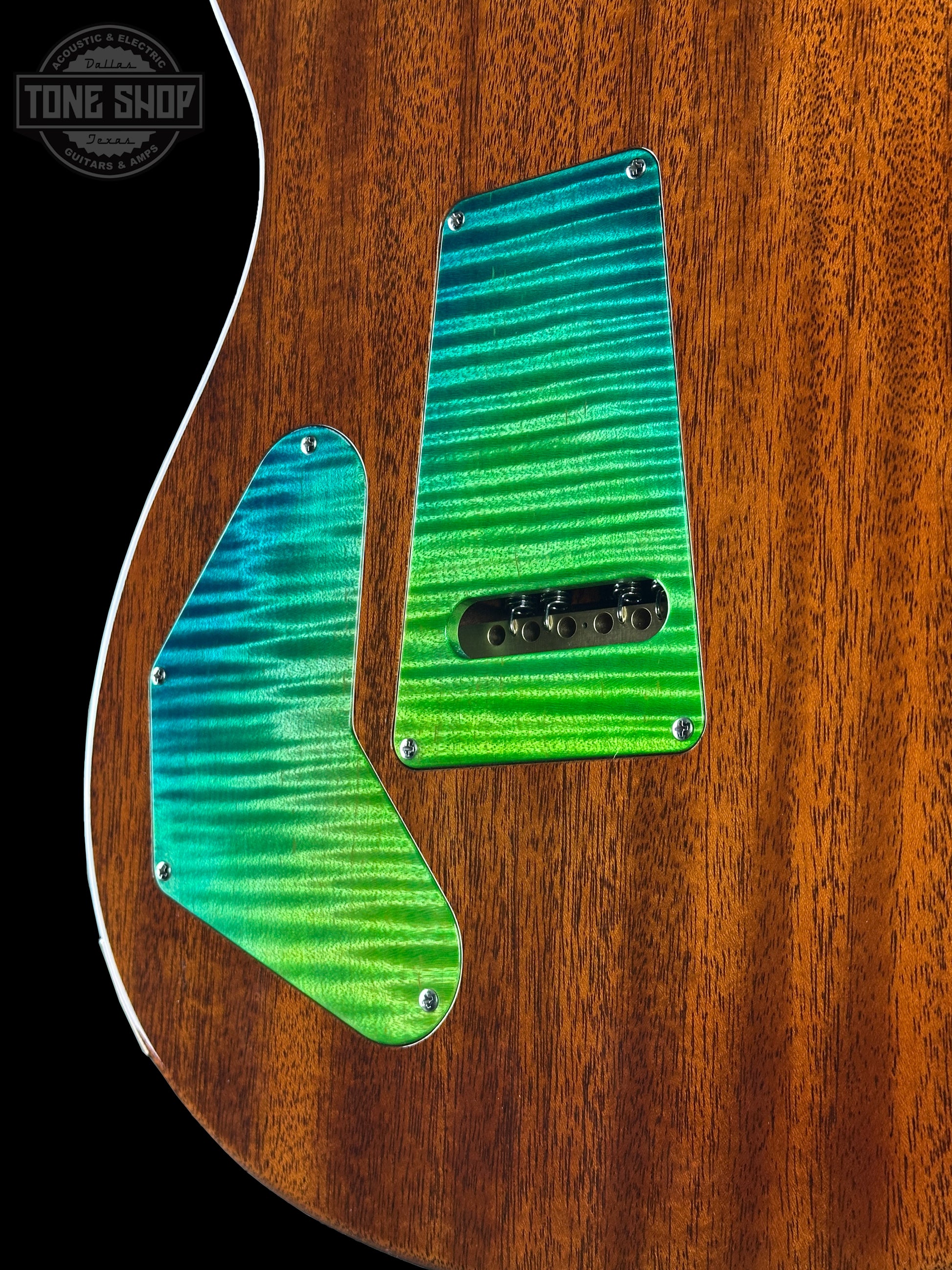 Close-up of a guitar with a wooden body and green pickguard.