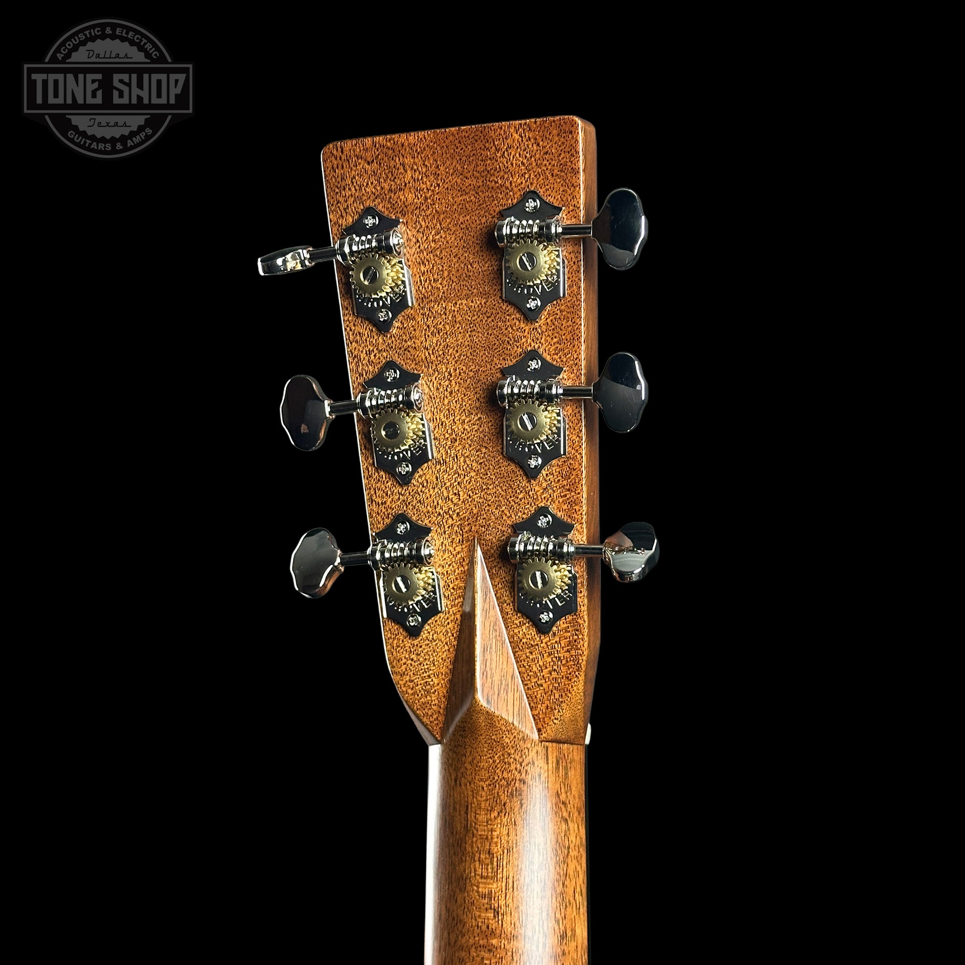 Close-up of a guitar headstock with tuning pegs on a black background, featuring the Tone Shop logo.