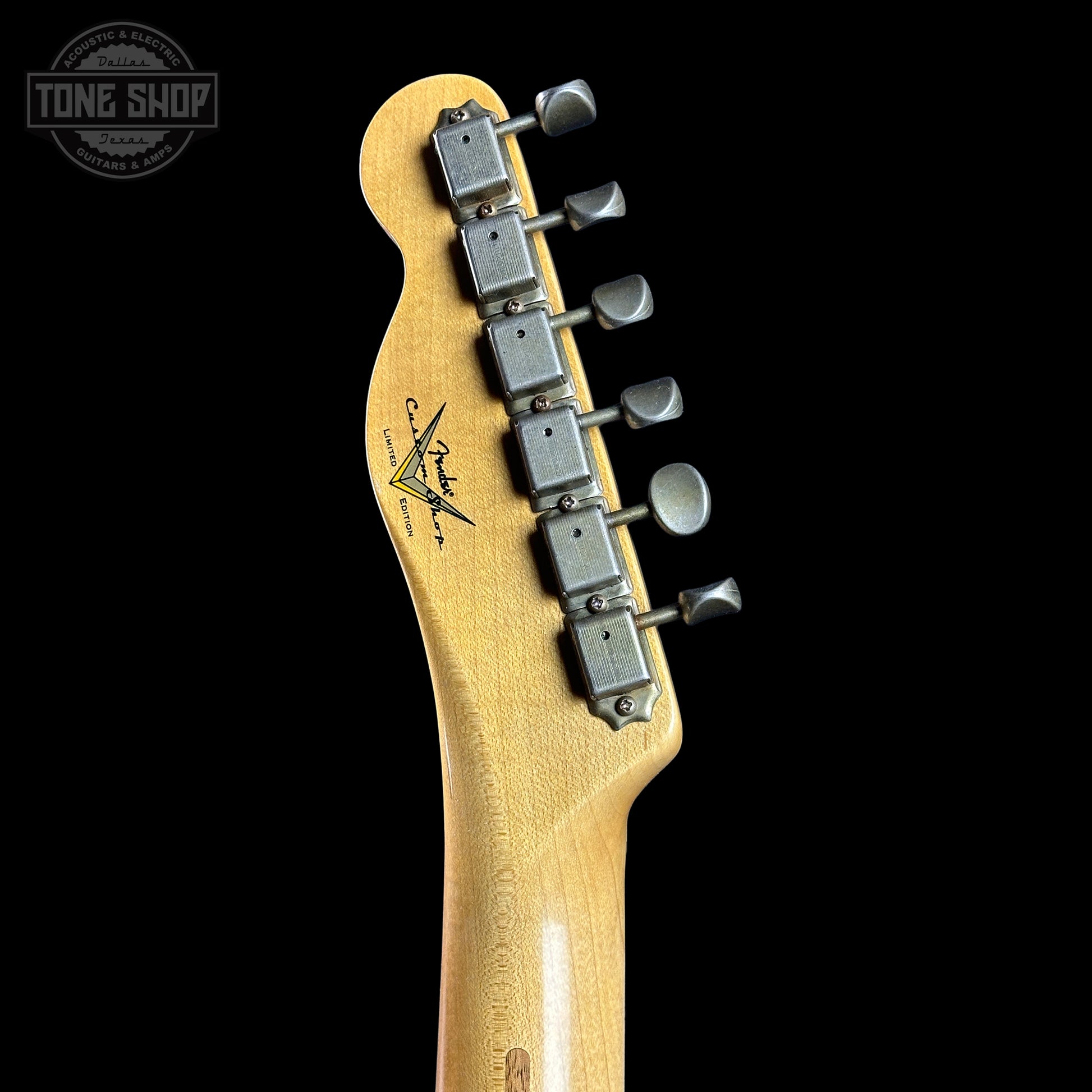 Guitar headstock with tuning pegs on a black background, featuring the Tone Shop logo.
