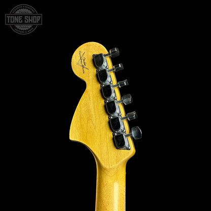 Close-up of a guitar headstock with tuning pegs on a black background, featuring the Tone Shop logo.