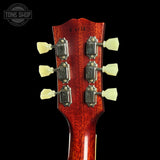 Close-up of a guitar headstock with tuning pegs on a black background, featuring the Tone Shop logo.