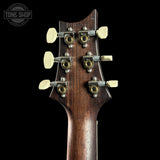 Close-up of a guitar headstock with tuning pegs on a black background, featuring the Tone Shop logo.
