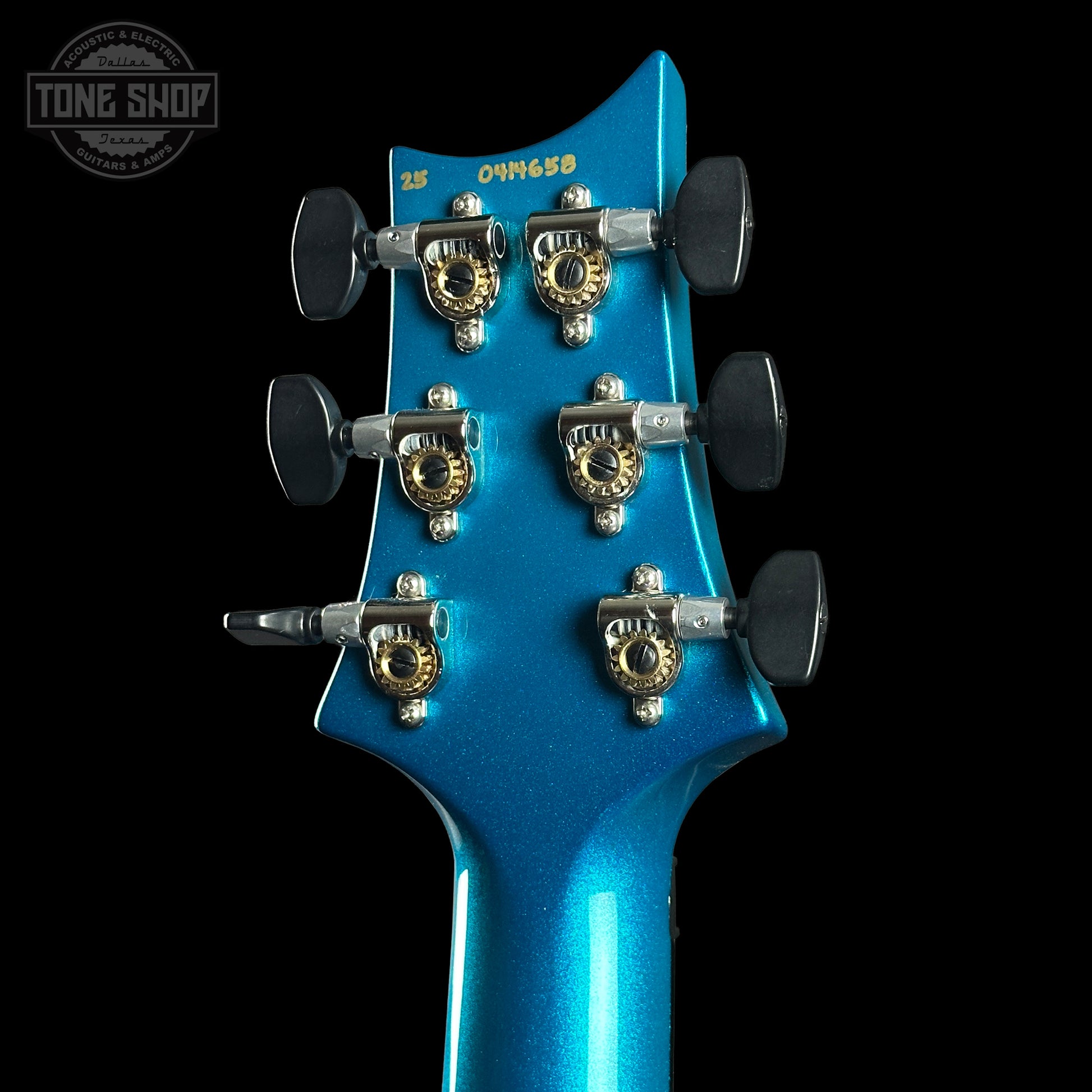 Close-up of a blue guitar headstock with tuning pegs on a black background, featuring 'Tone Shop' branding.