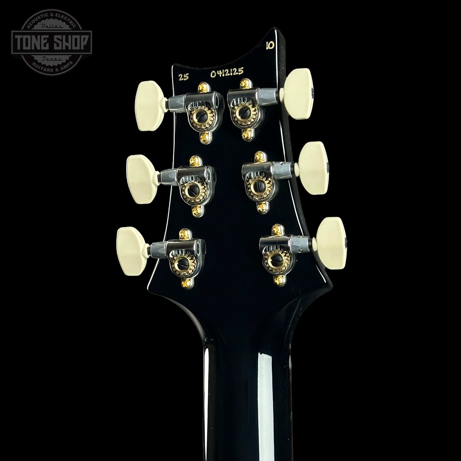 Close-up of a guitar headstock with tuning pegs on a black background, featuring the Tone Shop logo.