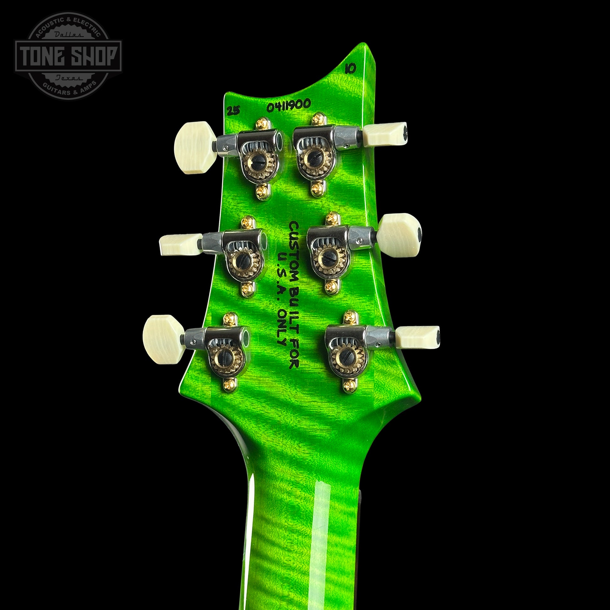 Close-up of a green guitar headstock with tuning pegs on a black background, featuring the Tone Shop logo.