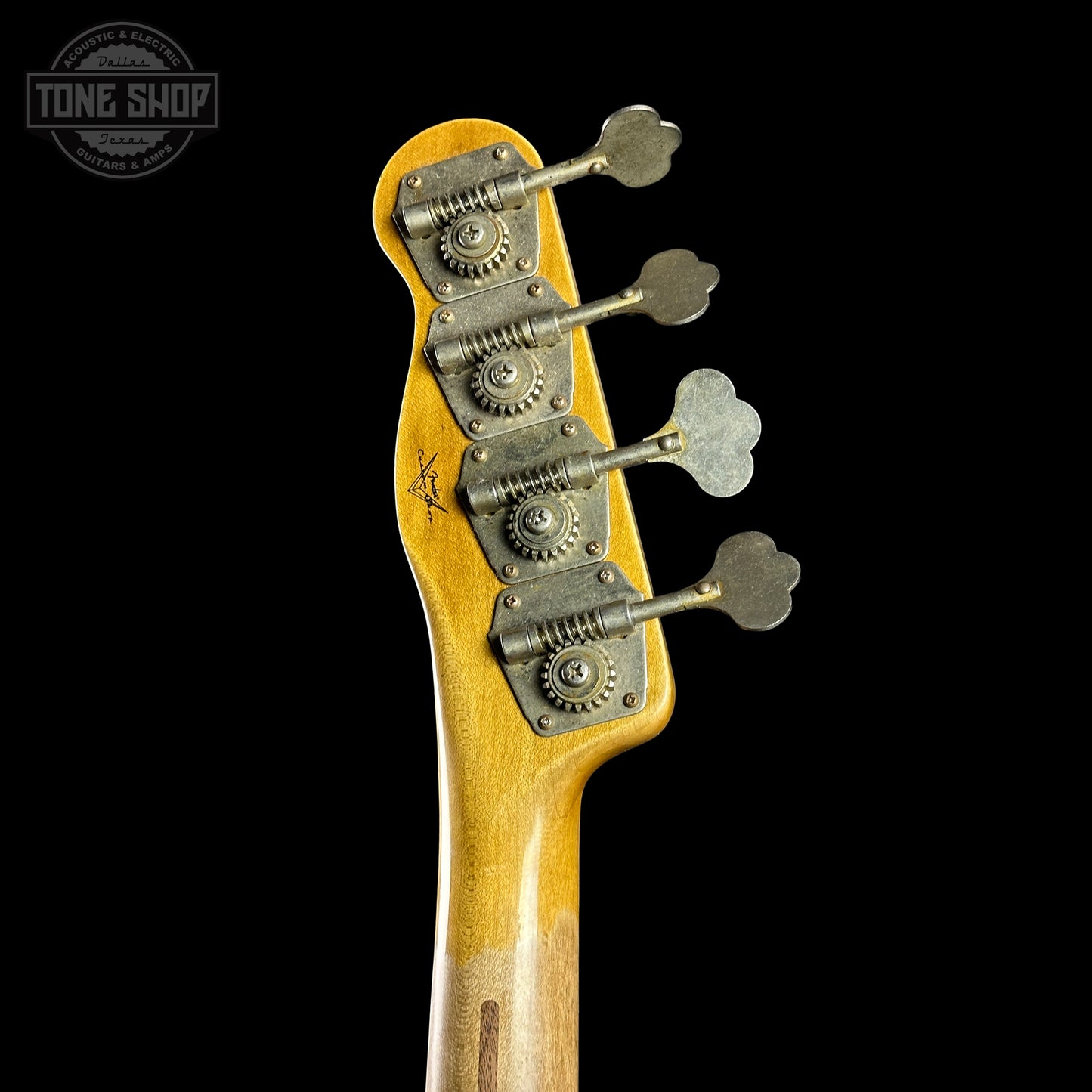 Close-up of a guitar headstock with tuning pegs on a black background, featuring the Tone Shop logo.
