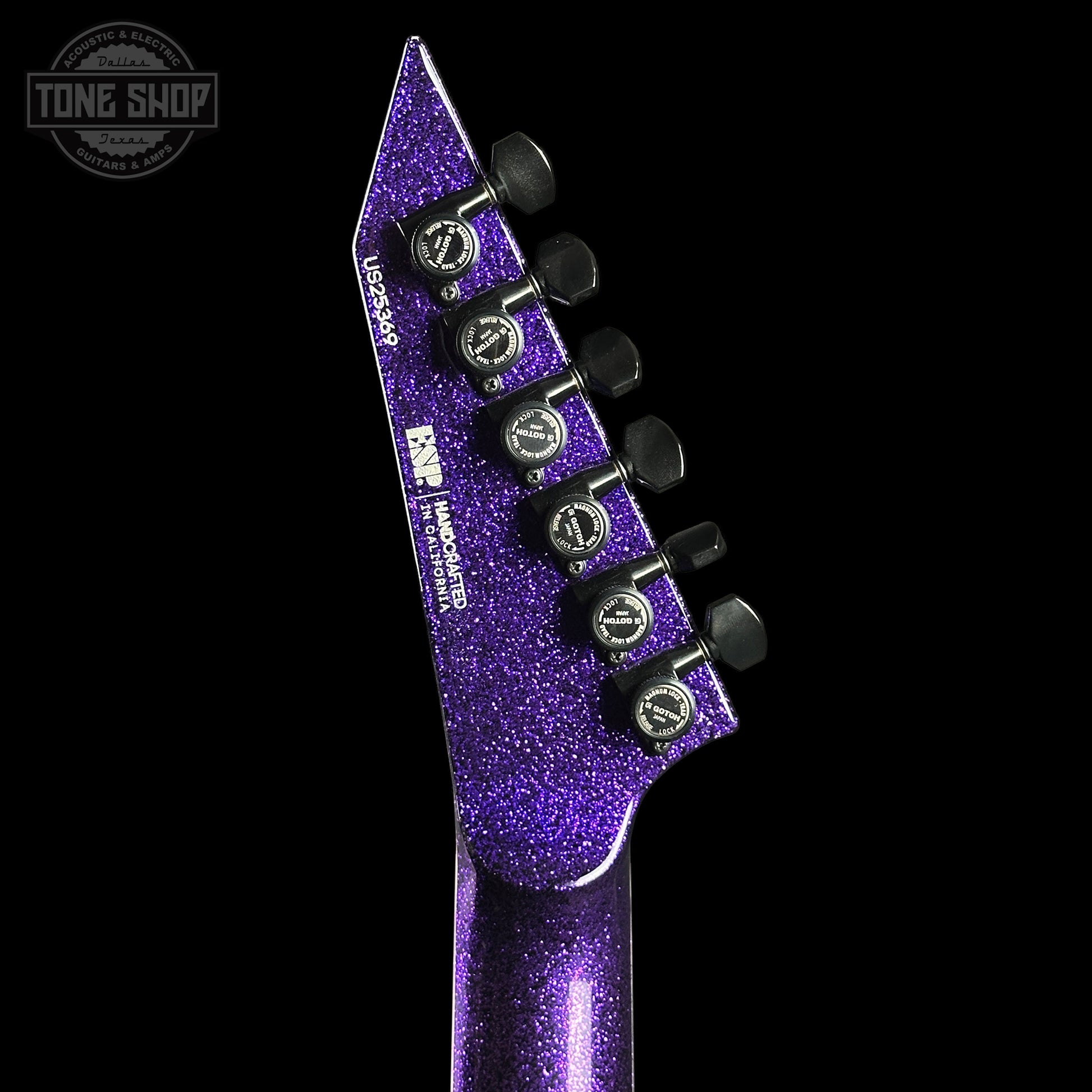 Close-up of a purple glittery guitar headstock with tuning pegs on a black background, featuring 'Tone Shop' logo.